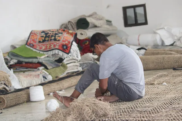 A maker working among rugs and yarn in the workshop